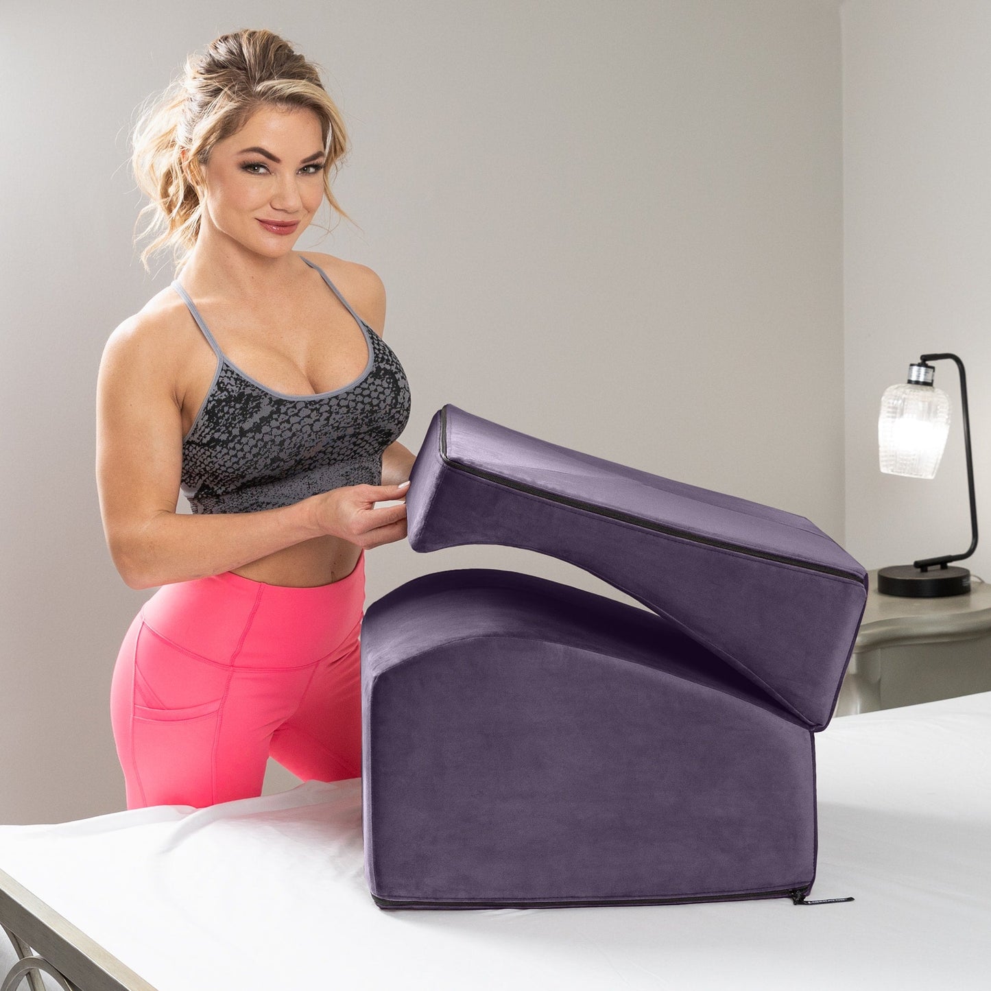 An aubergine Flip Ramp, Bedroom Furniture by Liberator folded up sitting on a bed next to a lady.